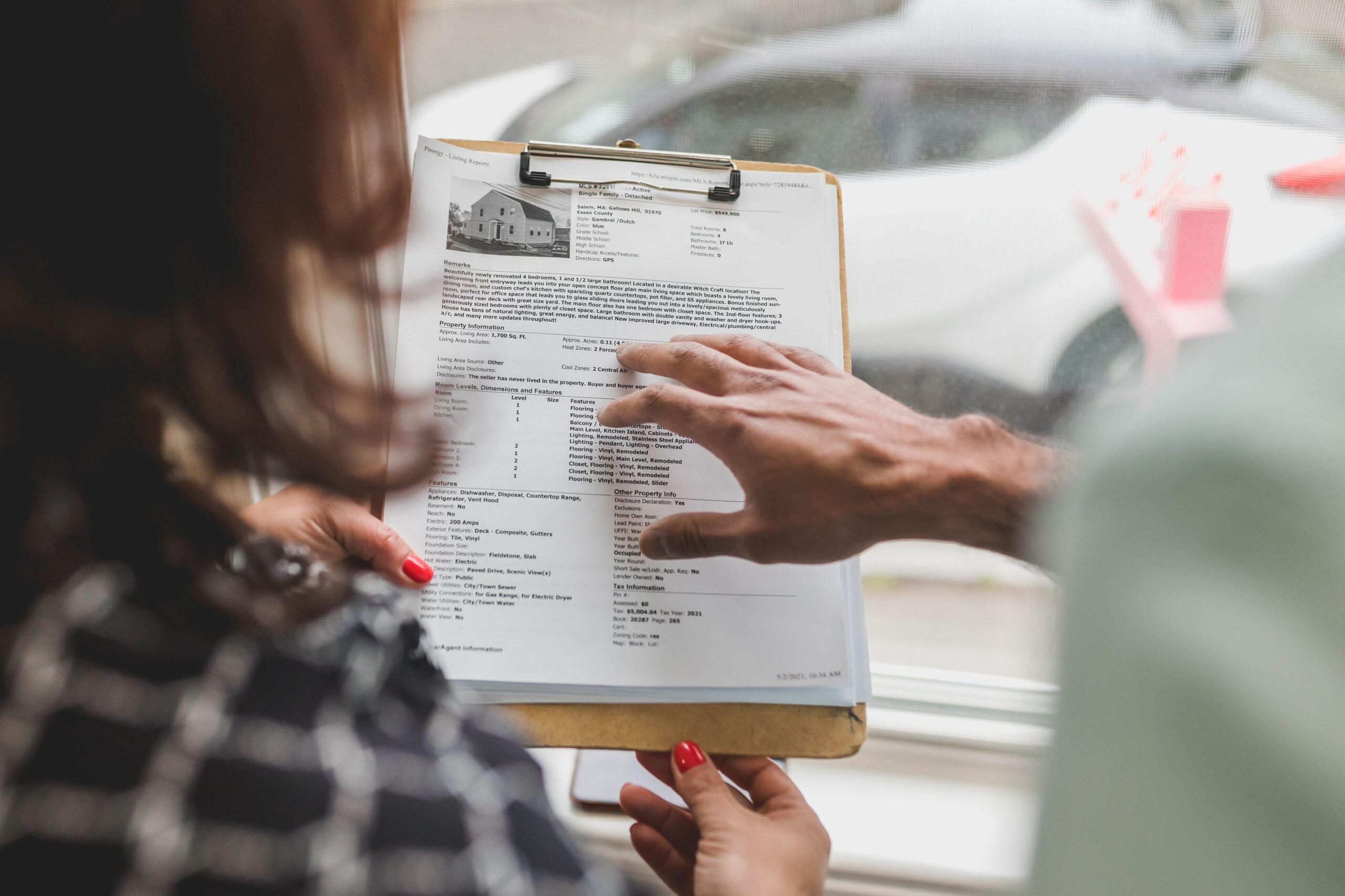 Real estate agent discussing property details with client using a clipboard indoors.